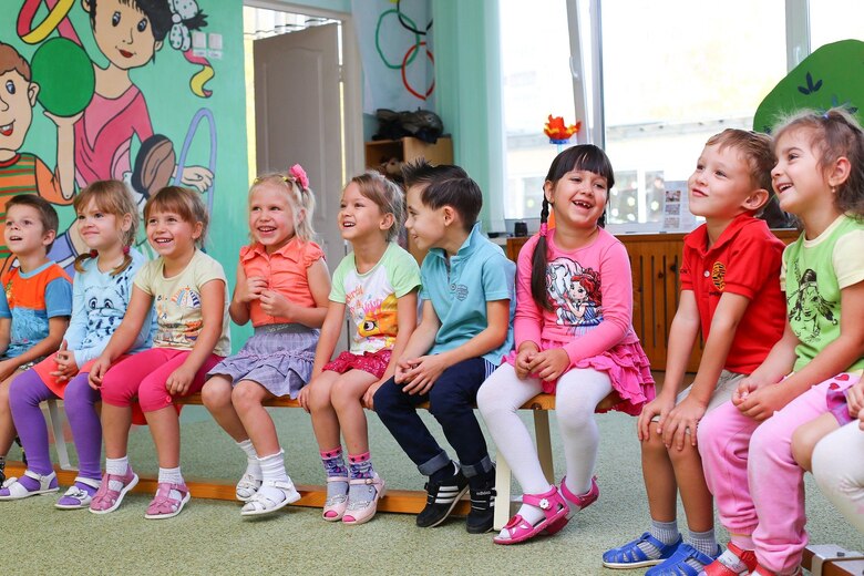 Kindergartenkinder sitzen auf einer Bank