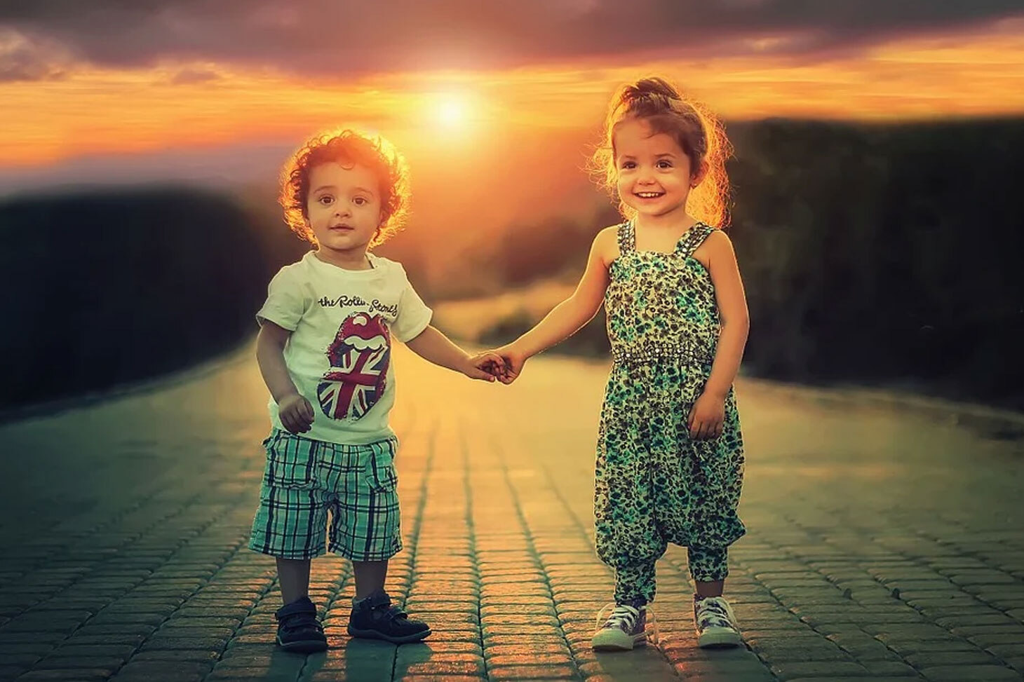2 дитини стоять пліч-о-пліч на фоні заходу сонця